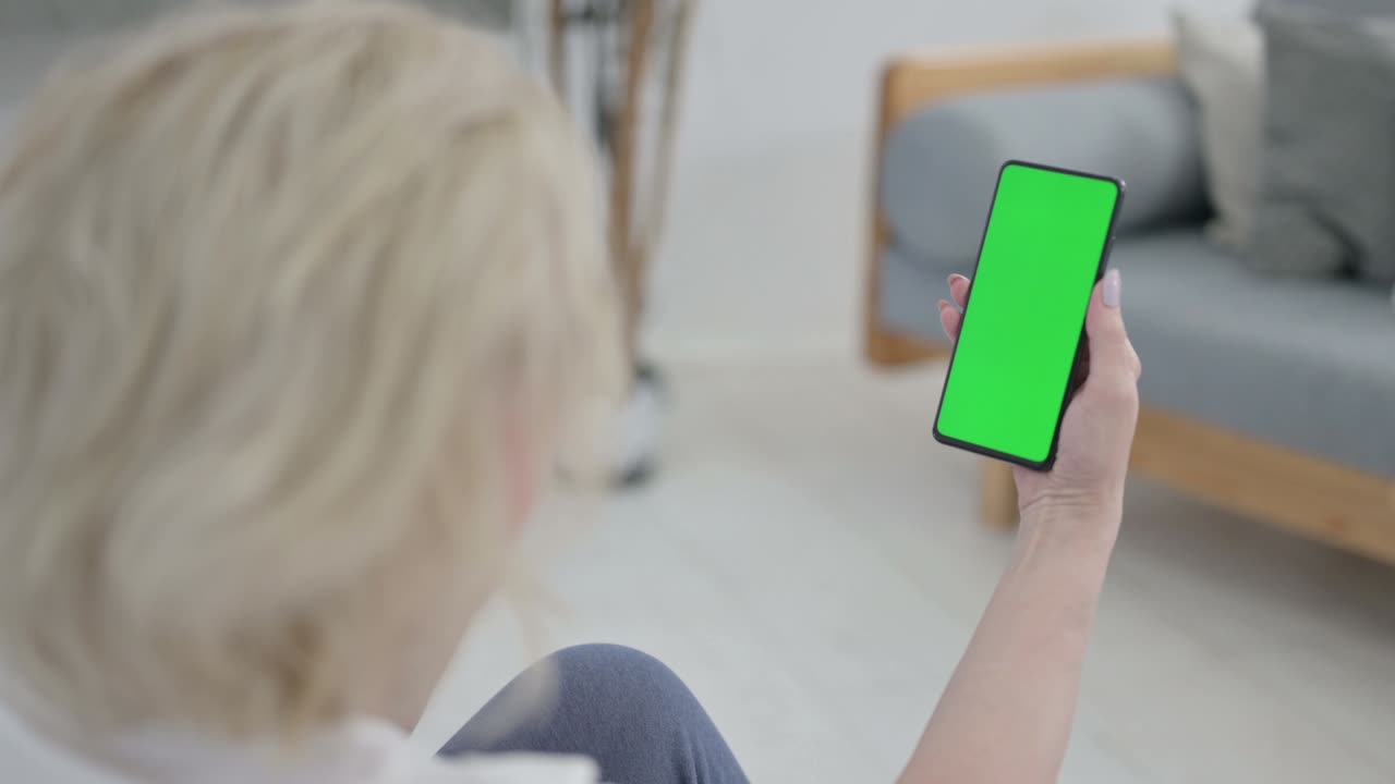 요가 매트 에 크로마 키 스크린 을 가진 스마트폰 을 보고 있는 노인 의 뒷면