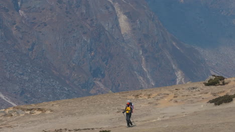 drone shot of a female tourist hiking in nepal’s khumbu region toward everest base camp. mt. cholatse stands in the backdrop, framing a wide himalayan landscape of adventure, travel, and tourism