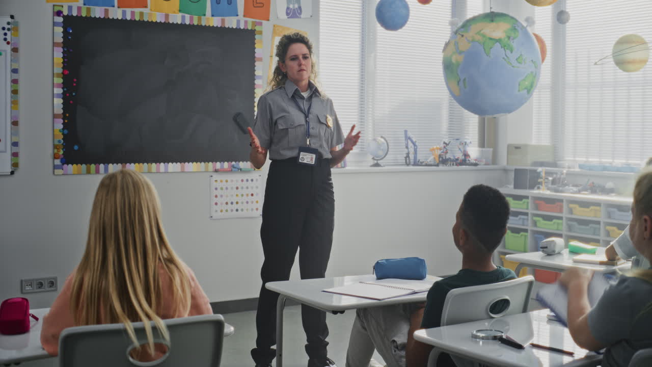American Female Policewoman Visiting Primary School Classroom Teaching Children About Discipline and