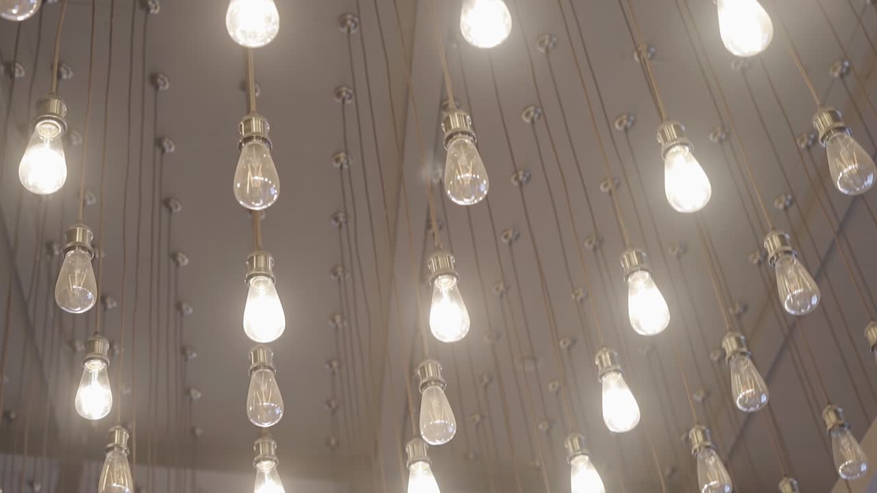 Many beautiful bright light bulbs decorate the ceiling of a large room. Cool light on the ceiling