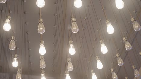 many beautiful bright light bulbs decorate the ceiling of a large room. cool light on the ceiling