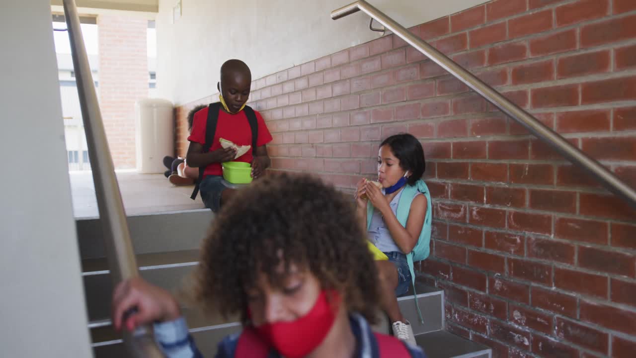 niño y niña comiendo el almuerzo de la caja de tiffin en las escaleras de la escuela