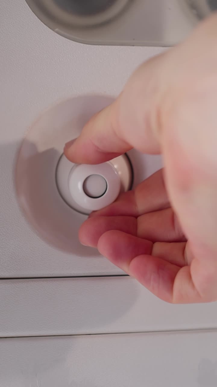 Close-up of a passenger adjusting an airplane air vent overhead, showing cabin comfort control and in-flight travel detail inside a commercial aircraft