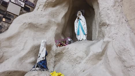 Closeup-shot-at-Virgin's-Mary-wall-of-hopes,-faithful-follower-pray-on-her-knees