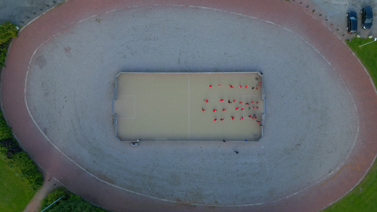 ejercicios de práctica de fútbol en una pequeña jaula de fútbol en un parque, tiro superior ancho con la cámara ascendiendo