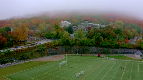 drone going down on the side of a synthetic soccer field near the mount-royal mountain in montreal on a foggy morning