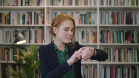 retrato de una joven feliz, pelirroja, mujer de negocios, pasante, riendo, alegre, disfrutando, revisando mensajes, usando reloj inteligente, tecnología móvil en la oficina de la biblioteca.