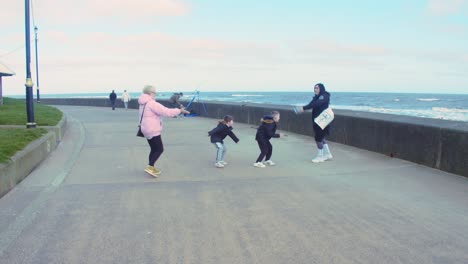happy family having fun and playing with ball at the seaside on a bright winters day. scarborough uk england