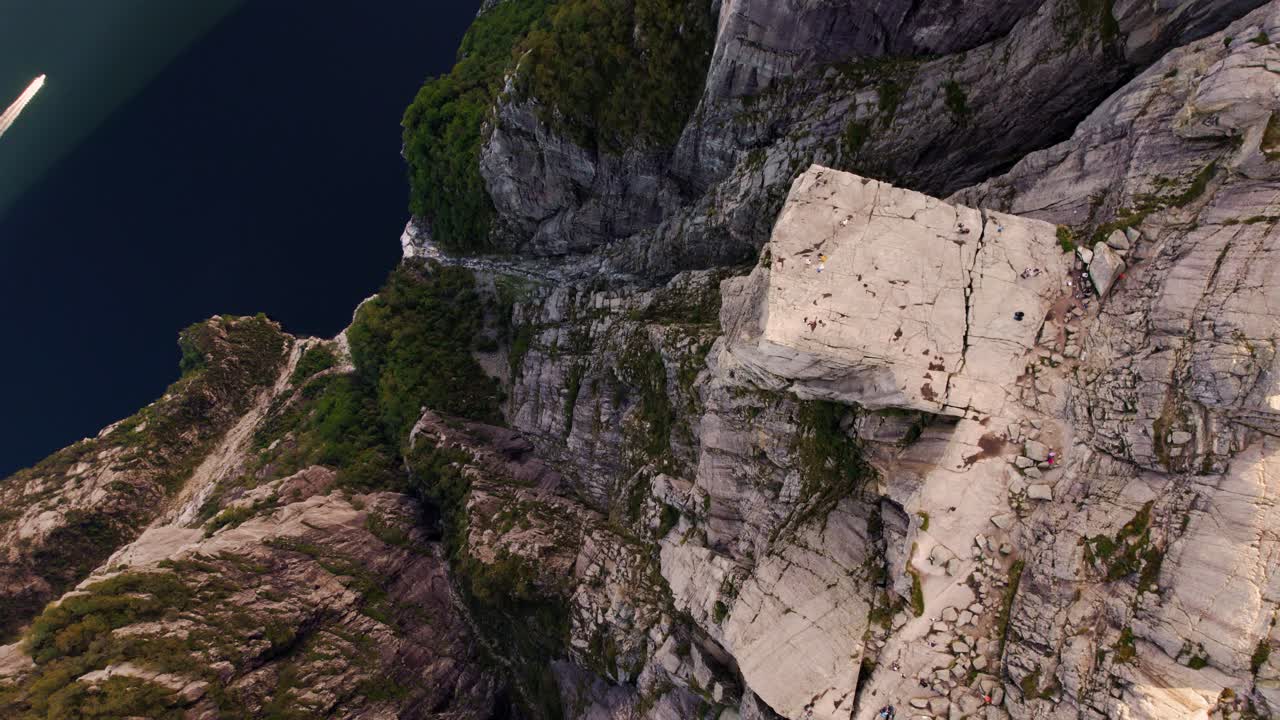 Scenic Norway landscape with Preikestolen cliff platform and tourists above calm Lysefjord waters.