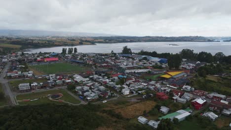 aerial view of chonchi, a chilean town and commune located in los lagos region, showing buildings, huillinco lake and soccer field