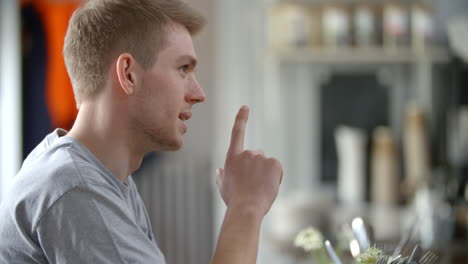 Young-man-sitting-in-a-cafe-talking,-side-view,-close-up