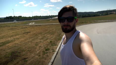 young man is riding on skateboard and recording himself on the street.