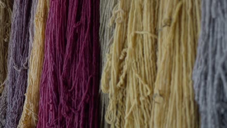 Slow-panning-shot-showing-multiple-batches-of-colourful-yarn-hanging-on-a-wall