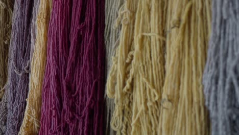 disparo lento que muestra varios lotes de hilos coloridos colgados en una pared