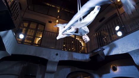 female aerialist spinning the silks in the cross back straddle pose