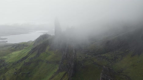 parallax drone shot of old man of storr landscape in scotland during cloudy and foggy day