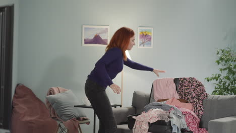 angry woman with ginger hair throws clothes into suitcase