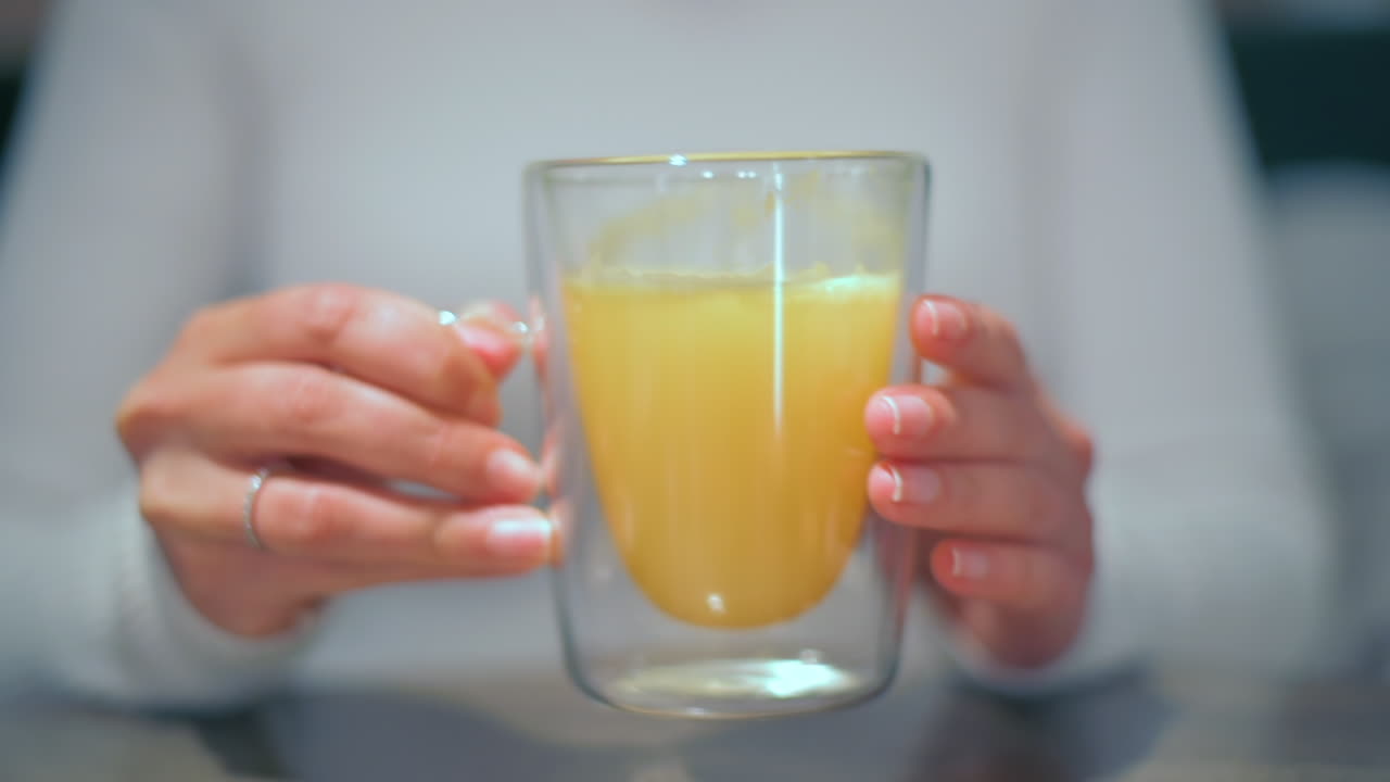 Mujer bebiendo un refresco de naranja en un vaso doble