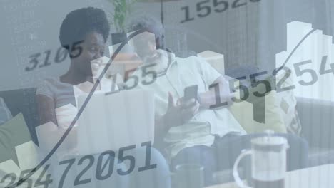 animation of changing numbers, graphs, african american couple using cellphone at home