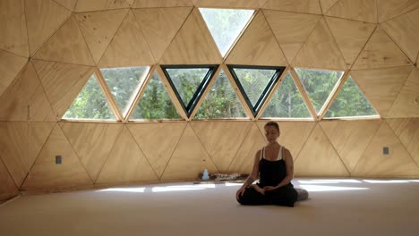 latina woman in a serene yoga session inside a geometric studio with a focus on calmness and mindfulness, offset at angle to the right