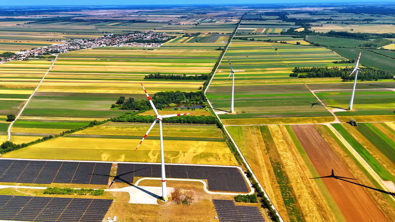 View on the vast picturesque countryside with wind farms and solar panels. Rural area at backdrop. Aerial perspective