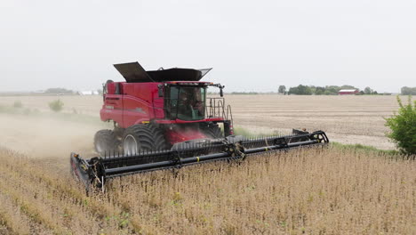 Red-Combine-Harvester-Cutting-Through-Soybean-Field-with-Dust-Rising