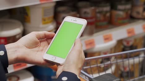 woman uses a smartphone with a green screen in a hardware store