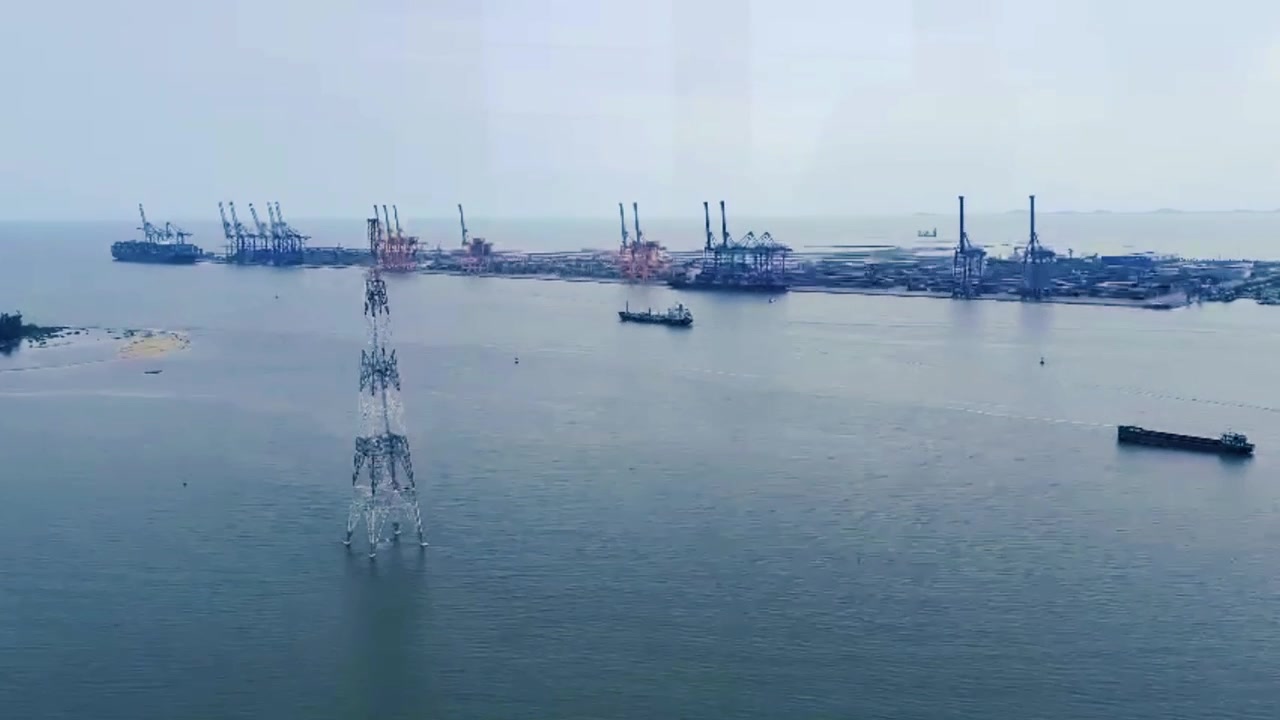 Aerial View of Industrial Port with Cargo Ships and Power Transmission Tower