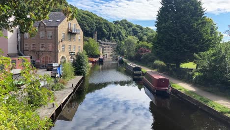 View-looking-down-an-English-canal-with-barge's,-river-boats,-longboats,-showing-old-mills-and-towpath