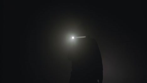 person with headlamp in fog