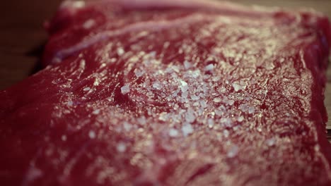 coarse sea salt on the raw meat steak close up