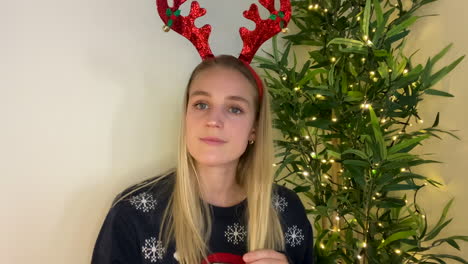 young woman joining christmas video call waving and talking directly to camera