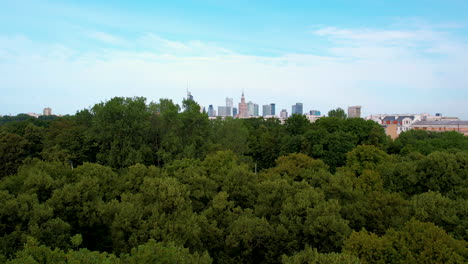 aerial pullback shot forest landscape and skyline of warsaw in background with blue sky