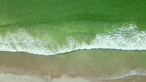 top down aerial trucking above gentle waves running onto pristine beach, weskus