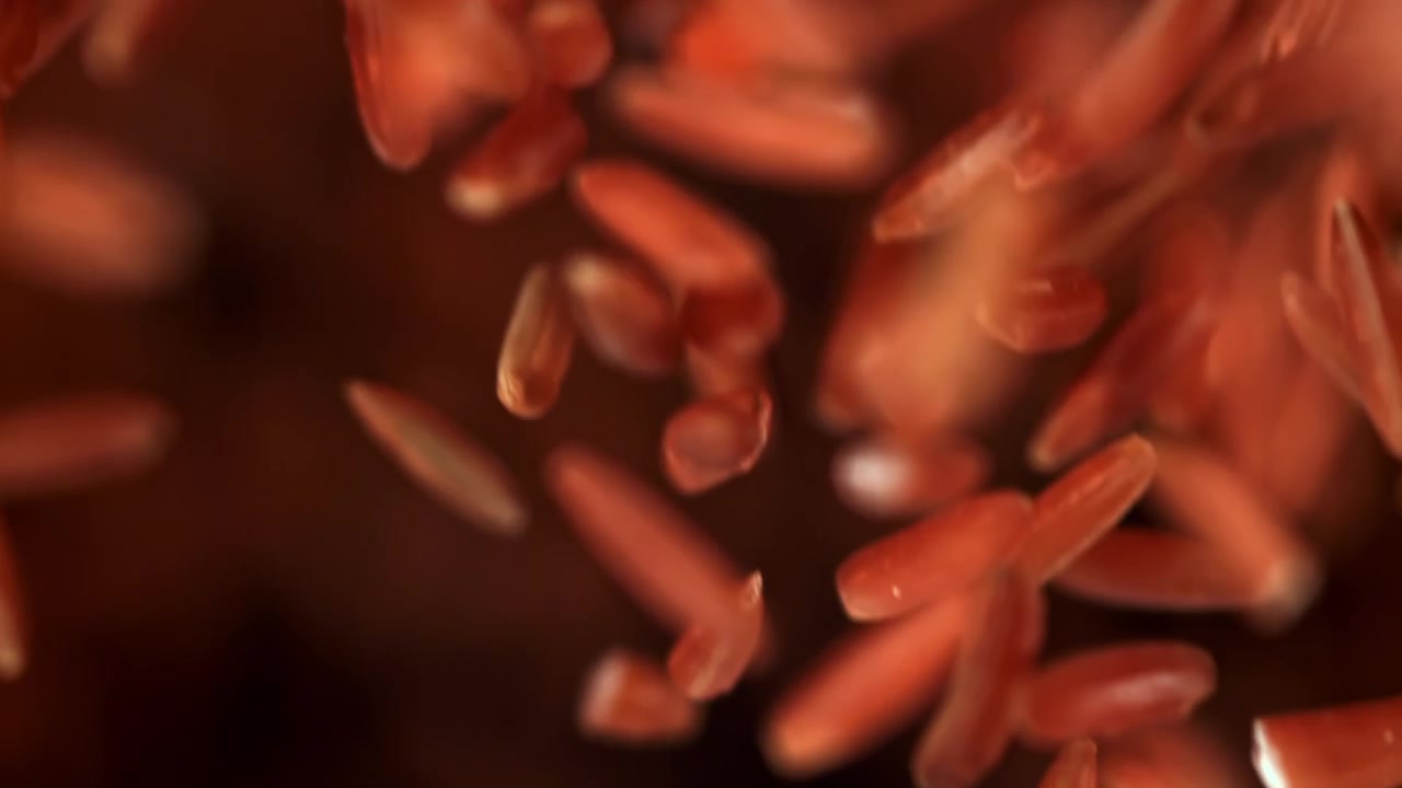 Red Rice Grains Falling in Slow Motion on a Dark Background