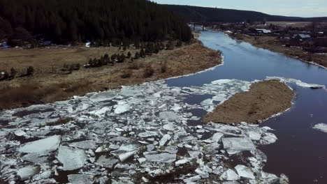 spring thaw on a river with melting ice and a village in the background