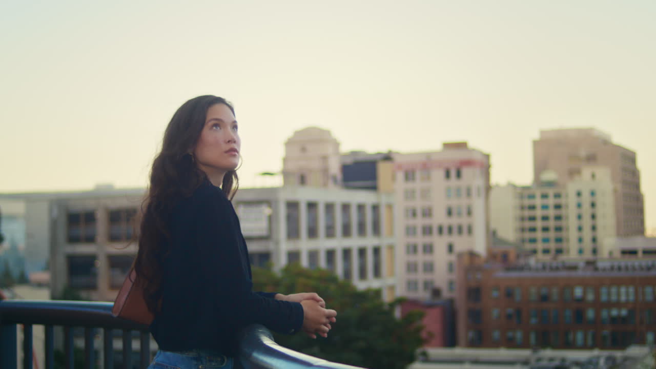 una chica asiática disfrutando de la vista de la ciudad al aire libre. una mujer tranquila de pie cerca de las barandillas.