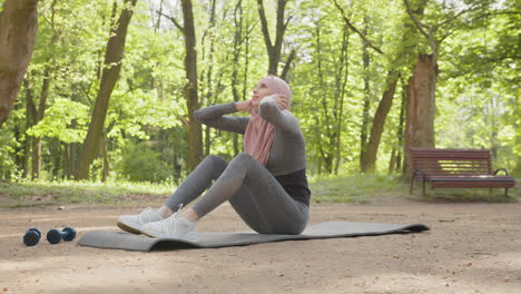 muslim woman doing sit-ups in a park