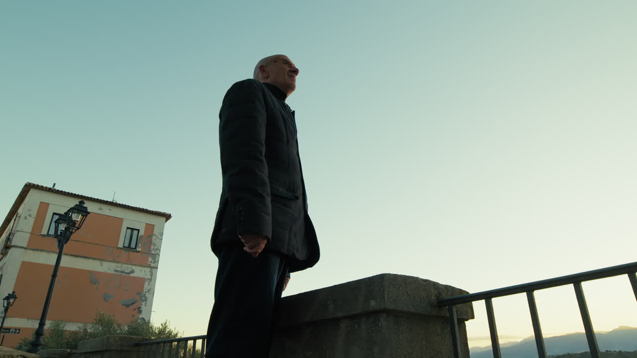 Sagoma di un uomo che guarda il tramonto dal balcone del suo paese natale