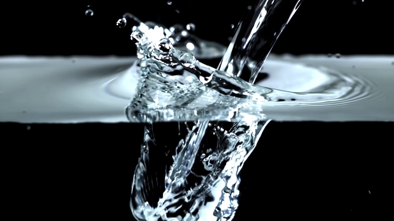 Movimento rallentato di acqua limpida che si versa e schizza su sfondo nero.