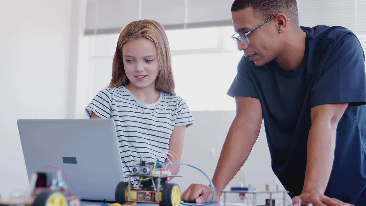 estudiante con el profesor construyendo un vehículo robot en la clase de codificación de computadoras después de la escuela