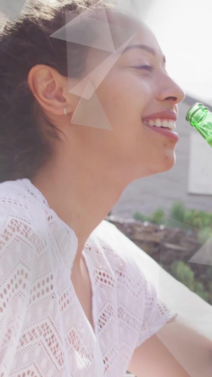 Video verticale: Una donna solleva una bottiglia verde, assaporando, mentre la telecamera si alza, con interfacce grafiche sul viso per il marketing.