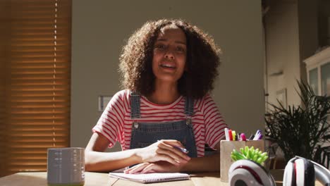 African-american-woman-sitting-at-desk-having-video-call-smiling