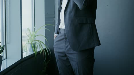 businessman in a grey suit standing near a window