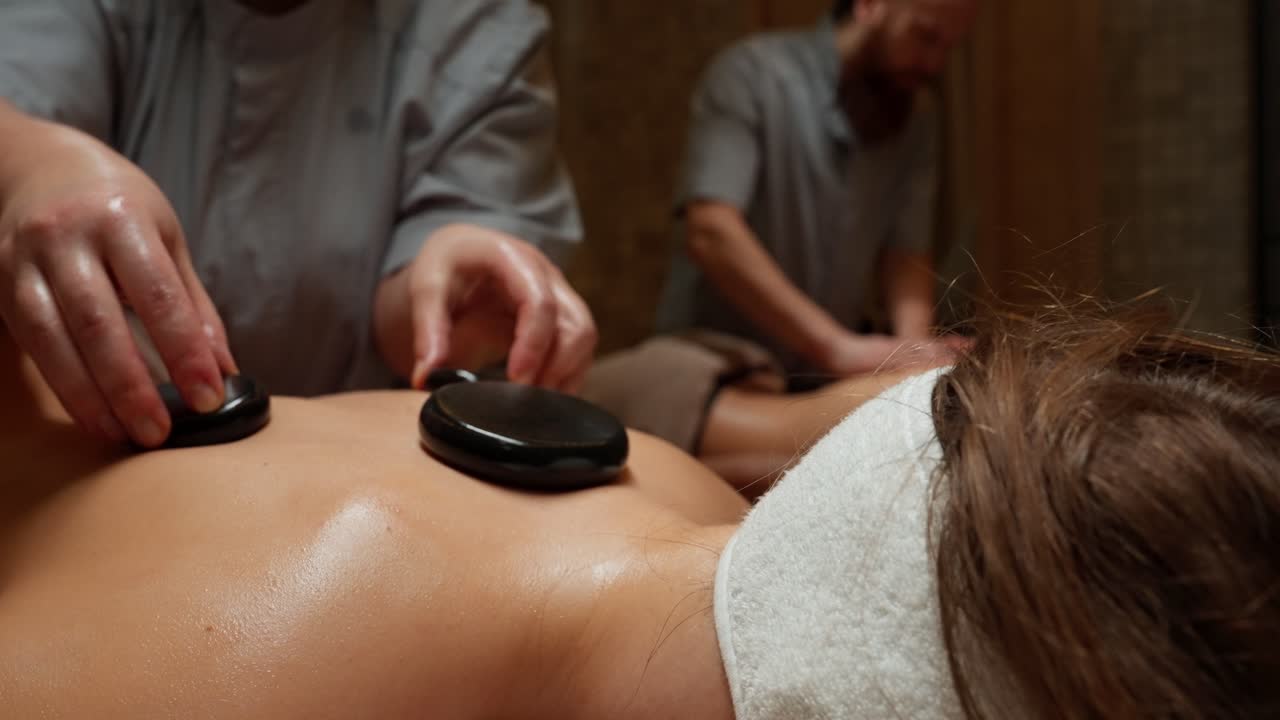 Nærbillede af hot stone massage på en persons ryg på et spa