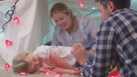 laughing parents with young daughter having fun in homemade camp in child's bedroom at home - shot on slow motion