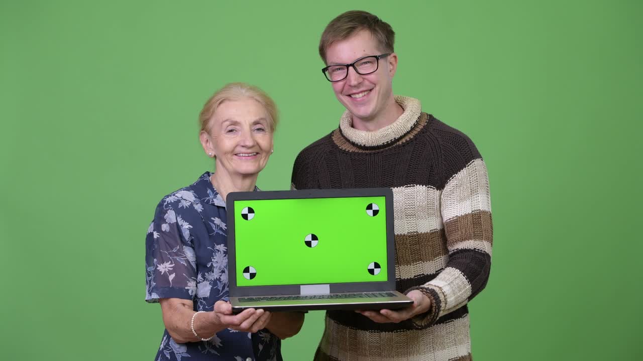 Happy grandmother and grandson showing laptop together