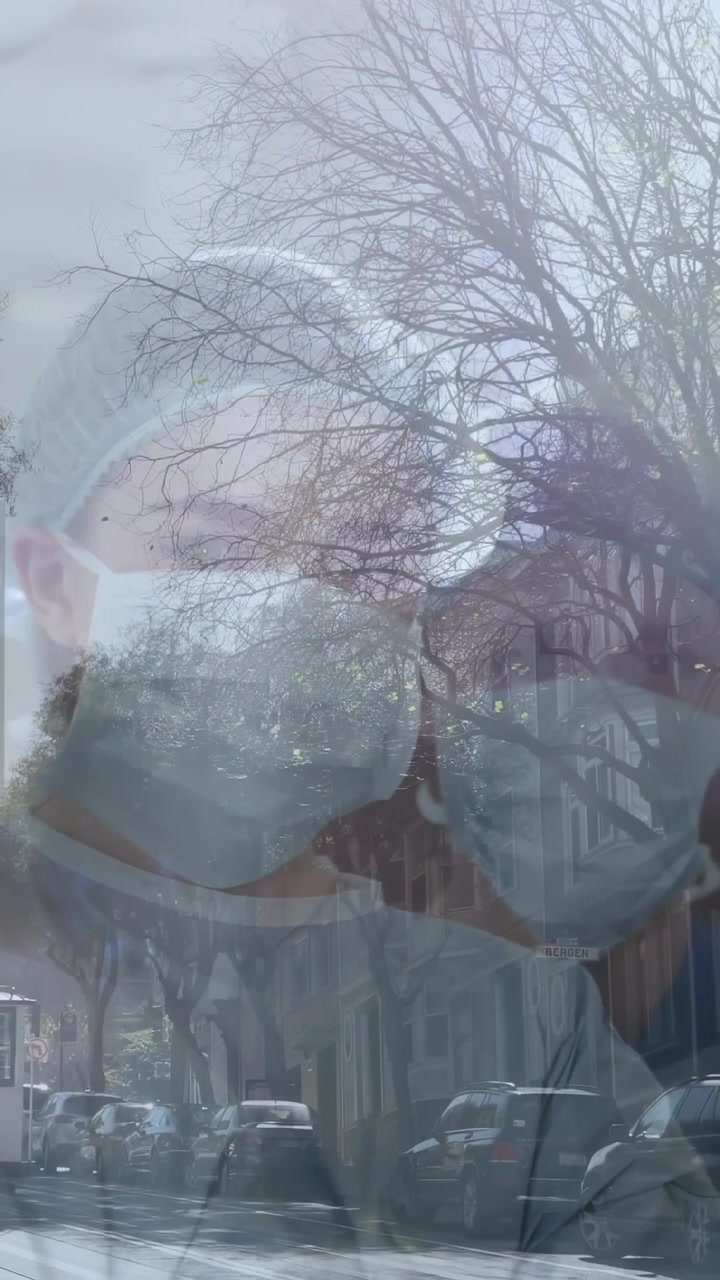 Vertikales Video: Zwei maskierte Mitarbeiter erscheinen als Glas-Overlay über der Straße durchs Fenster, Gesundheit zeigend.