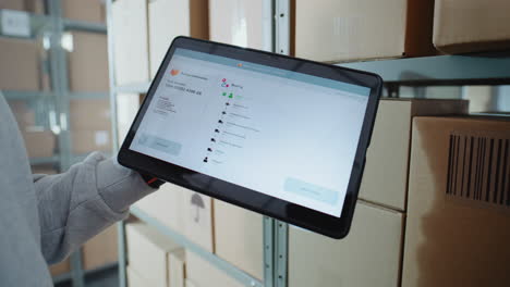 warehouse worker using tablet for package tracking