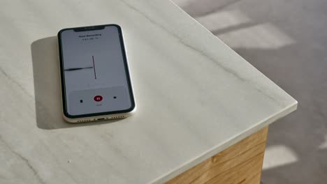smart mobile phone on kitchen counter recording conversation with voice notes app. close up on cellphone with recording application listening to person talking capturing sound waves in apartment room